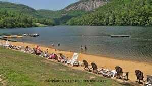 Ein Seeuferbild vom Sapphire Valley Rec Center mit Sandstrand, Liegestühlen und einer Anlegestelle.