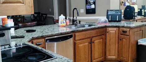 A kitchen with granite countertops, wooden cabinets, a dishwasher, and a stove.
