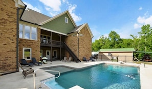 A house overlooking a heated pool with outdoor seating and a covered patio area.