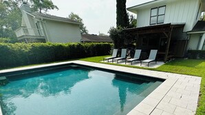 En rektangulär swimmingpool med klart blått vatten, omgiven av en terrass med kakelplattor.