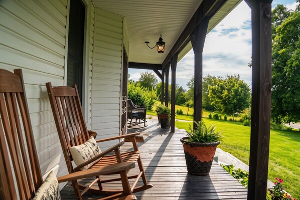 A wooden porch with rocking chairs and potted plants.