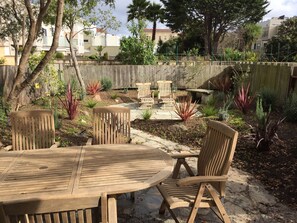 Relax in a serene outdoor space surrounded by lush greenery and a rustic wooden table.