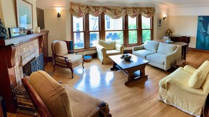 A living room with a fireplace, two sofas, a coffee table, and a painting on the wall. - Spacious and Charming Marina District Home Steps from the Bay (SF)