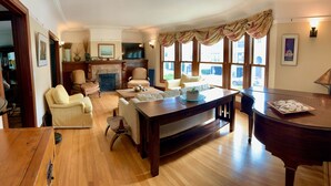 A spacious living room with a fireplace, comfortable seating, and large windows. - Spacious and Charming Marina District Home Steps from the Bay (SF)