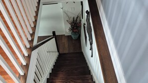 A wooden staircase with white railings and a potted plant at the top.