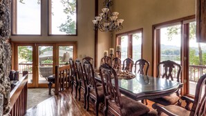 A dining area with a glass table, wooden chairs, and a chandelier.