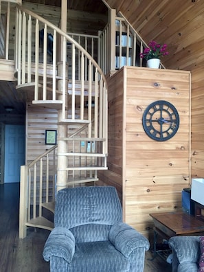 Cozy interior space with a spiral staircase, comfortable armchair, and wooden desk.
