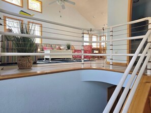 A spacious indoor area with a boxing ring, a ceiling fan, and a dining area with chairs and a table.