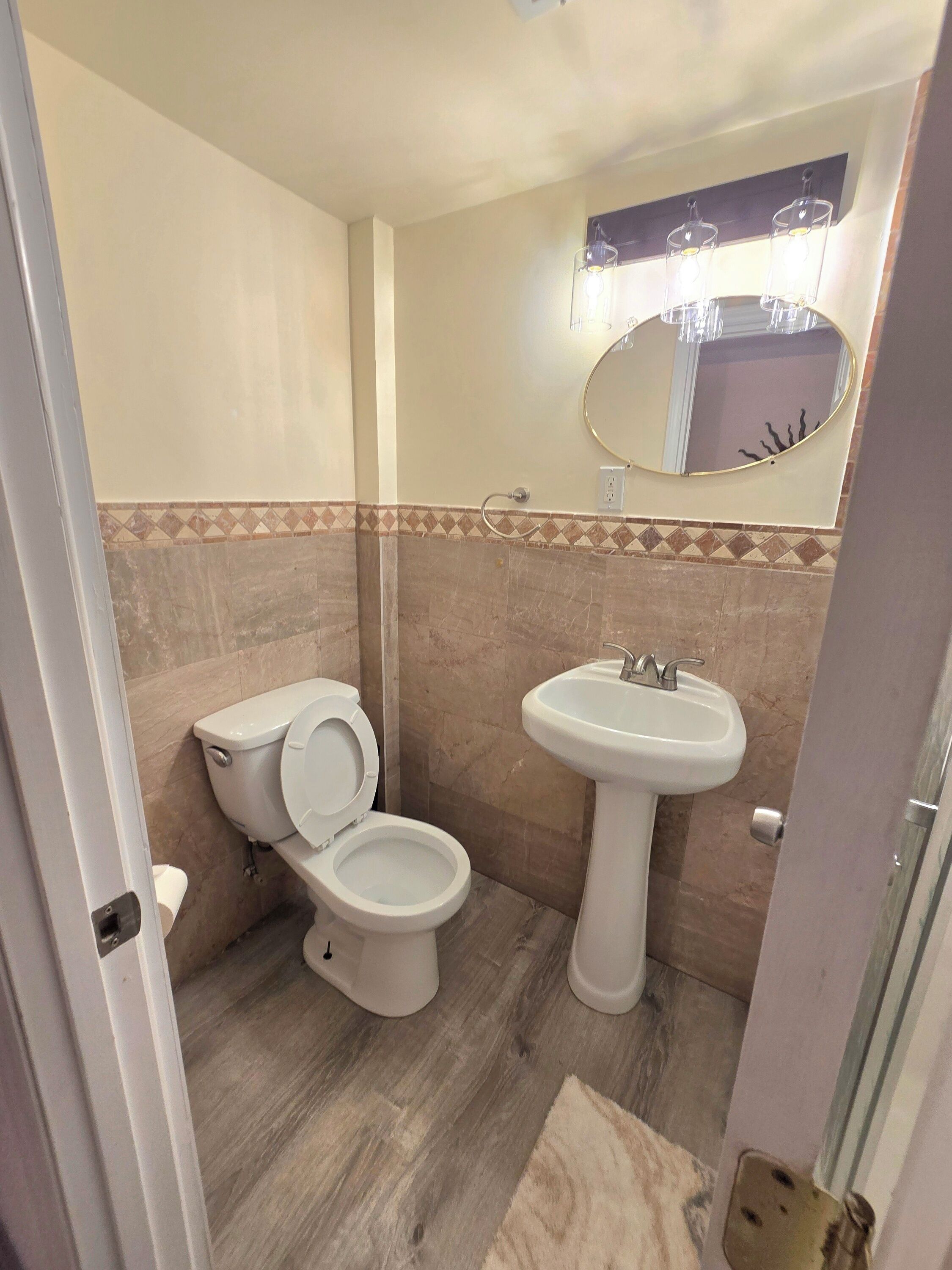 A bathroom with a toilet, sink, and mirror.
