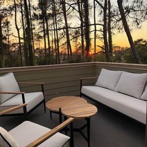 A balcony with a sofa, chairs, and a round table.
