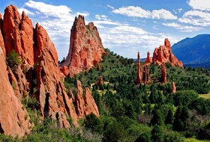A landscape with prominent red rock formations and dense green vegetation. - Lake Front, Rockies, Hiking, Mtn Biking! Aug. & Sept. Deals! (Monument)