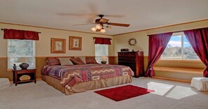 A bedroom with a bed, a nightstand, a dresser, a window with curtains, and a ceiling fan. - Lake Front, Rockies, Hiking, Mtn Biking! Aug. & Sept. Deals! (Monument)