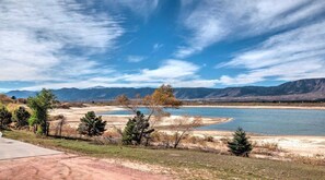 A river with mountains in the background, a clear sky, and a dirt path leading to a grassy area with trees. - Lake Front, Rockies, Hiking, Mtn Biking! Aug. & Sept. Deals! (Monument)