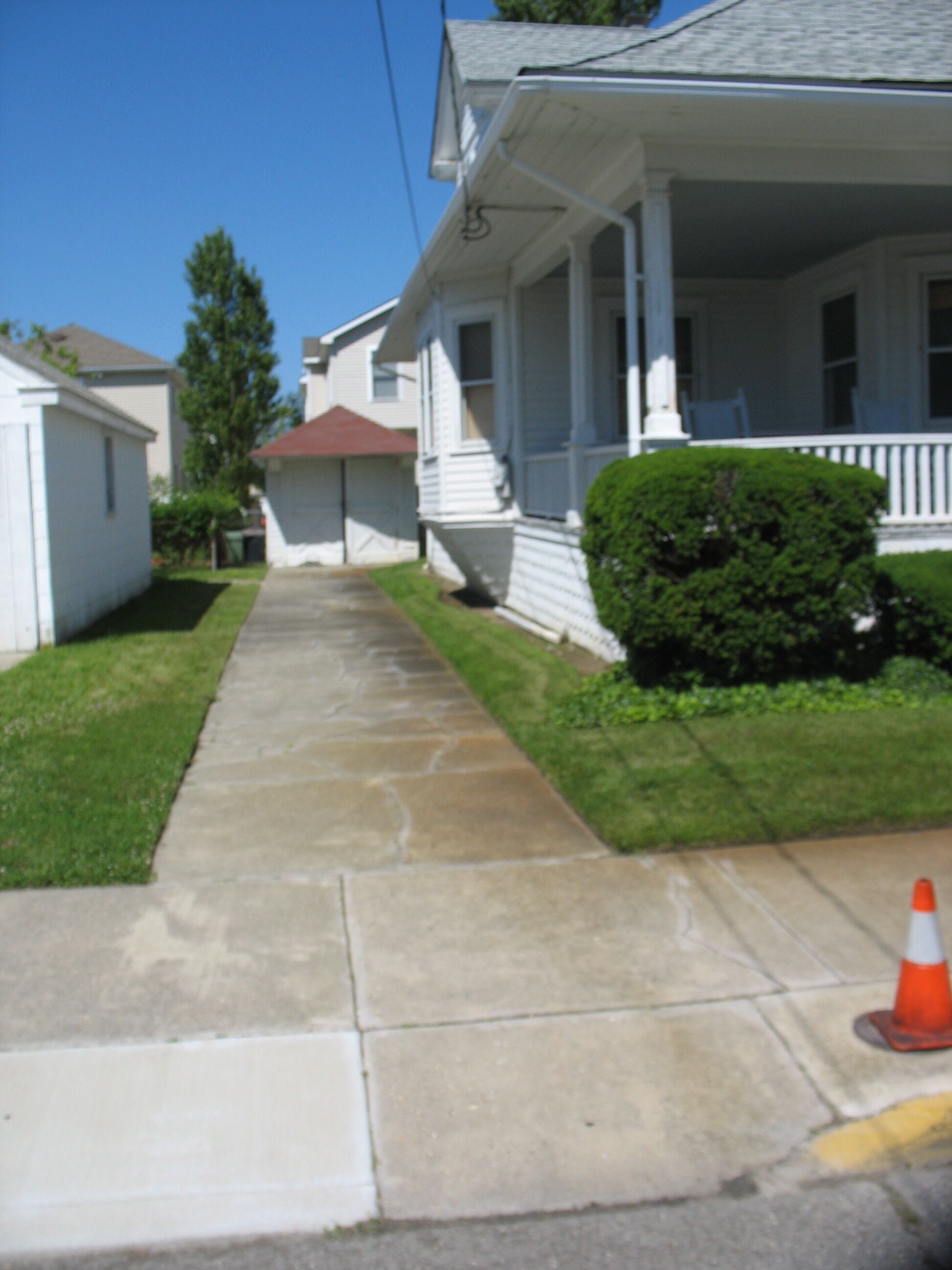 A residential house with a front porch, a small front yard, and a sidewalk.