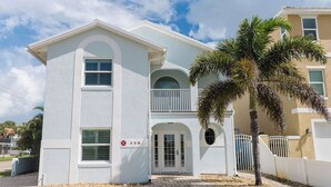 A two-story building with a white facade, a balcony, and a palm tree in front. - 5 BD, 3 bath, 200 Yards to Cocoa Beach (Cocoa Beach)