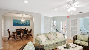 A spacious living room with a dining area, a ceiling fan, and a staircase leading to another level. - 5 BD, 3 bath, 200 Yards to Cocoa Beach (Cocoa Beach)