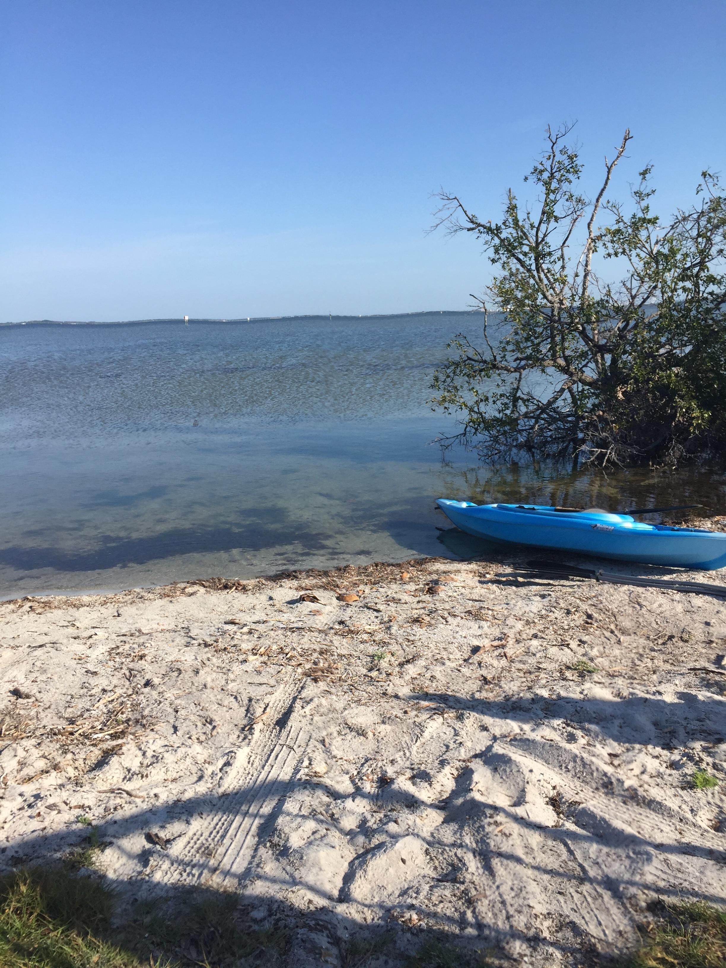 Una playa arenosa con una vista despejada del mar y un kayak azul.
