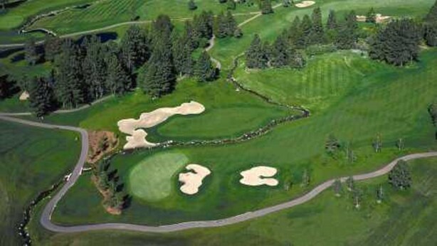 Golfkenttä, jonka yhteydessä on järvi, metsäalueita ja taustalla kohoavia vuoria.