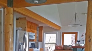 Una cocina amplia con armarios de madera, un refrigerador de acero inoxidable y una lámpara colgante.