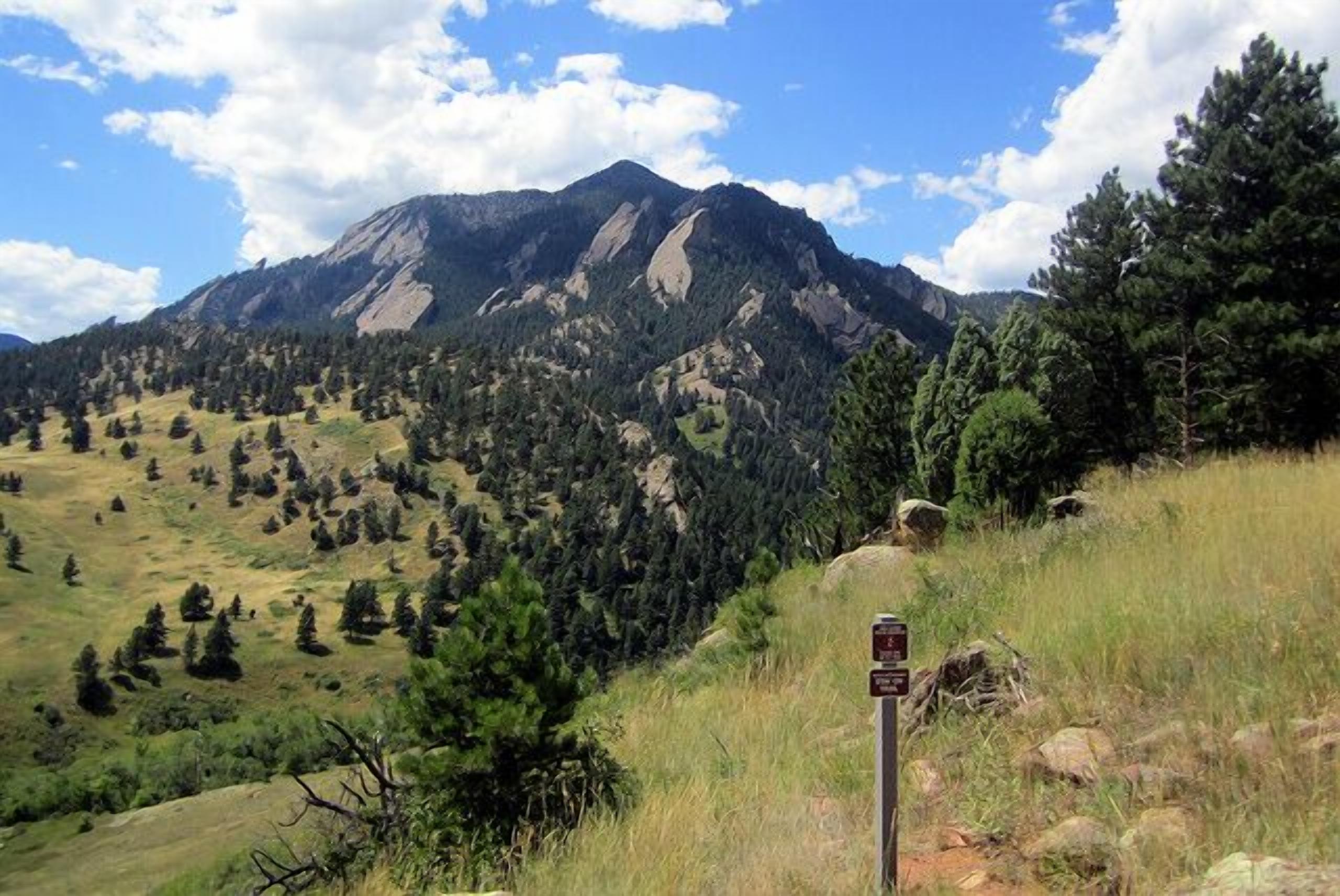 A mountain landscape with a signpost in the foreground.