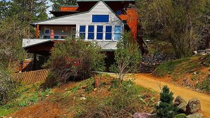 Una casa moderna de dos pisos con un porche delantero amplio y ventanas grandes.