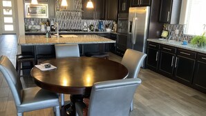 A modern kitchen with dark cabinets, stainless steel appliances, and a central island with seating. - Child, Handicapable, Senior friendly Newer 4 bedroom (Peoria)