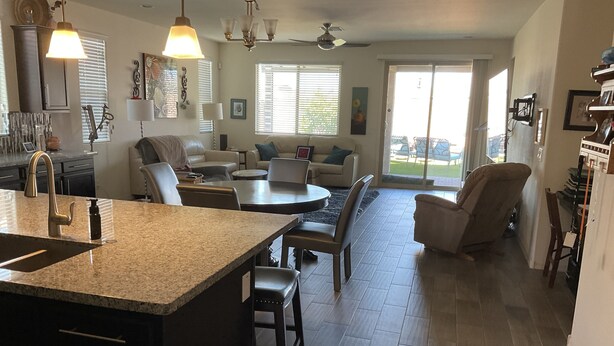 A spacious kitchen with granite countertops, a dining area with a round table, and a large island. There are multiple seating areas with sofas and chairs. - Child, Handicapable, Senior friendly Newer 4 bedroom (Peoria)
