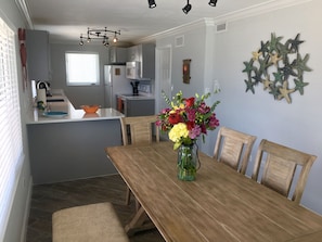 A modern kitchen with grey cabinets, a wooden dining table, and a vase of flowers. - SPECTACULAR! PRIVATE POOL, OCEAN FRONT, & DOCK Sister house nextdoor VRBO#770357 (Marathon)