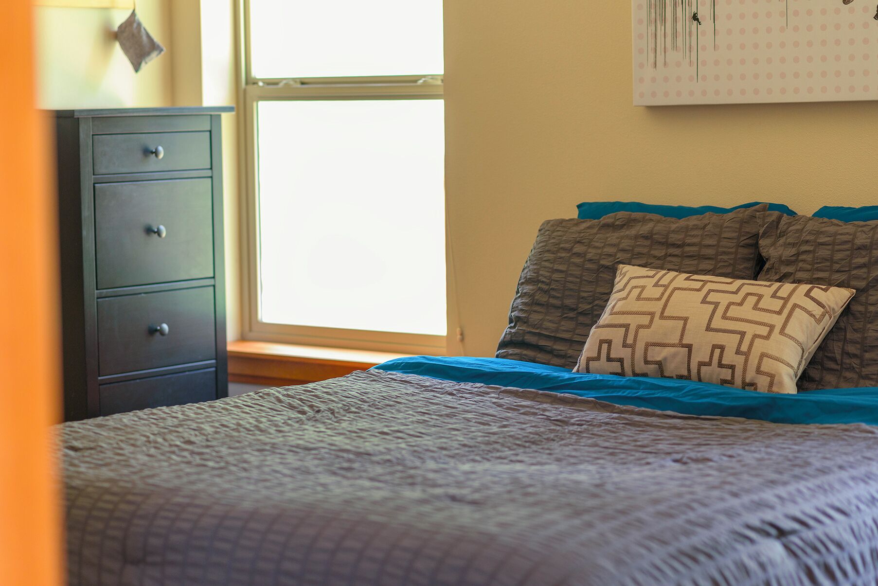 Une chambre à coucher avec un lit, une commode et une fenêtre.