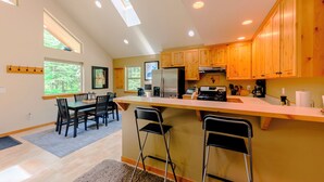 Una cocina moderna con armarios de madera, una isla central y un comedor con sillas.