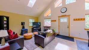 Una sala de estar con chimenea, sofá, televisión y estanterías.