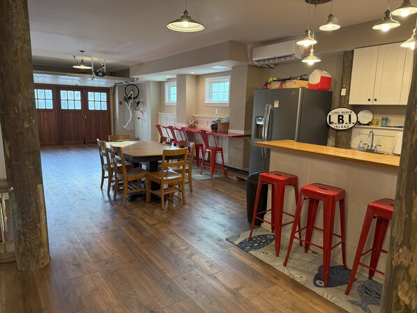 A spacious kitchen with a wooden dining table, red bar stools, and a refrigerator. - Bayfront w/dock, fire pit, Beach Haven Park, LBI. Easy 2 blocks to beach (Long Beach Township)