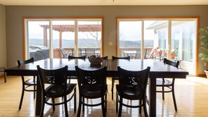 A dining area with a large table and chairs, large windows with a view of the outdoors, and a ceiling fan. - Welcome to “Majestic View” – The View of a Lifetime! (Burnside)