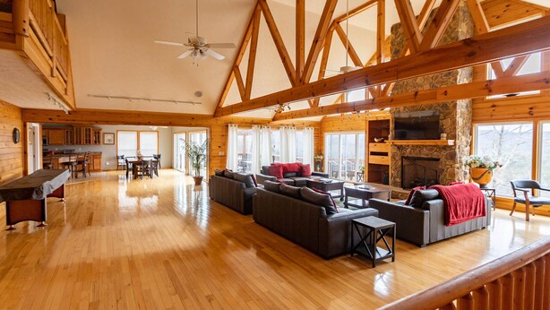 A spacious living area with wooden floors, a fireplace, and a stone wall. - Welcome to “Majestic View” – The View of a Lifetime! (Burnside)