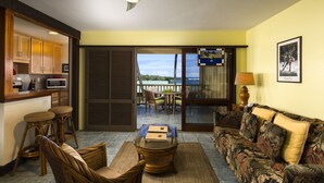 A room with a kitchen, dining area, and a balcony with a view.
