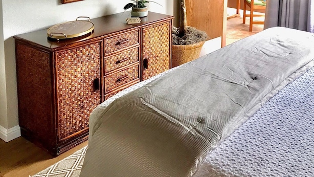 Ein Schlafzimmer mit einem Bett, einem Schminktisch, einem Spiegel und einem Topf mit Pflanze.