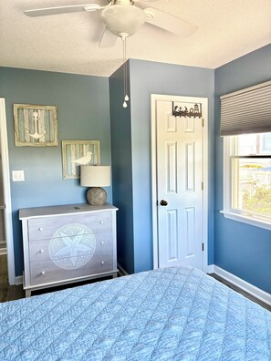A bedroom with a bed, dresser, ceiling fan, and a door with a window. - Keystone West West - Emerald Isle Paradise  (Emerald Isle)