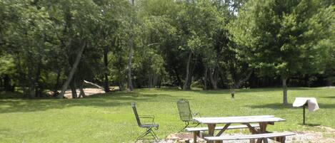 A picnic area with two metal chairs and a wooden picnic table.