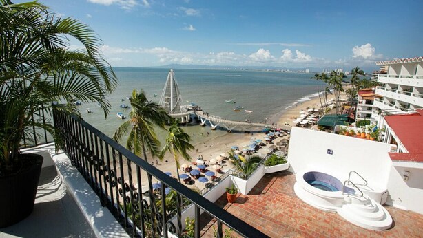Blick auf einen Strand mit einer Brücke, Palmen und einem Pool.