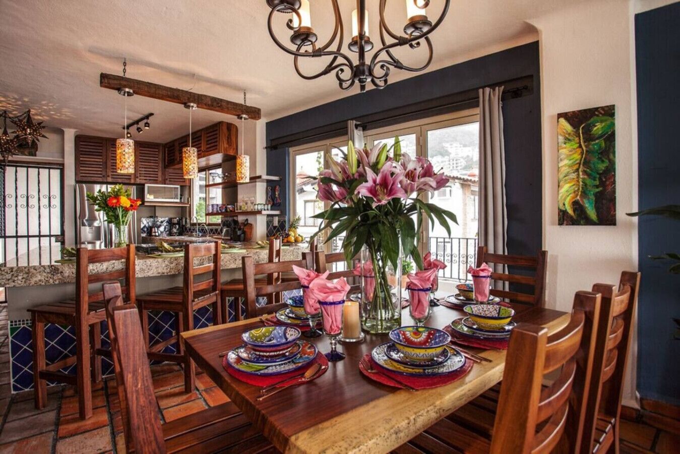 A dining area with wooden furniture, a chandelier, and a large window with a view.