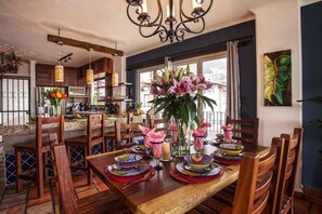 Un espace repas avec des meubles en bois, un lustre et une grande fenêtre donnant sur un beau paysage.