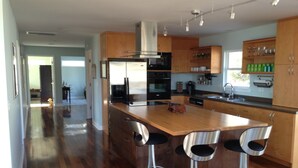 Une cuisine moderne avec des meubles en bois, des appareils en acier inoxydable et un îlot central doté de tabourets de bar.