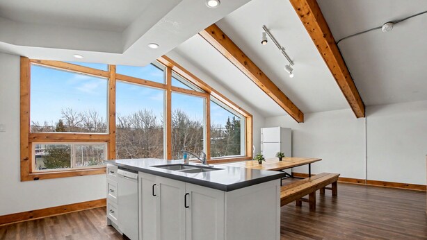 A modern kitchen with wooden beams, large windows, and a central island. - Birch View Chalet Blue Mountain (The Blue Mountains)