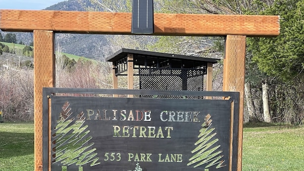 Letrero para Palisade Creek Retreat con fondo negro y letras blancas, ubicado en 553 Park Lane.