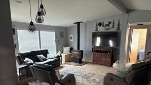Una sala de estar con un conjunto de sofá, una televisión, una chimenea y un comedor con una mesa.