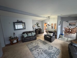 A living room with a sofa, a coffee table, and a rug. There is a dining area with a table and chairs.