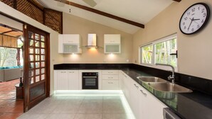 A modern kitchen with white cabinets, a black countertop, a built-in oven, and a wall-mounted clock. - Casa Serena, Playa Grande. A private beachfront property! (Playa Grande)