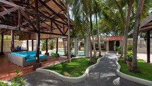 A covered outdoor area with a pool, seating, and palm trees. - Casa Serena, Playa Grande. A private beachfront property! (Playa Grande)