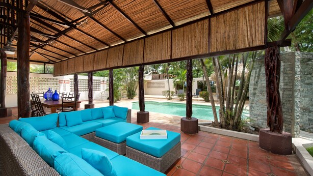 A covered outdoor seating area with a pool, wicker furniture, and a view of the pool and surrounding greenery. - Casa Serena, Playa Grande. A private beachfront property! (Playa Grande)