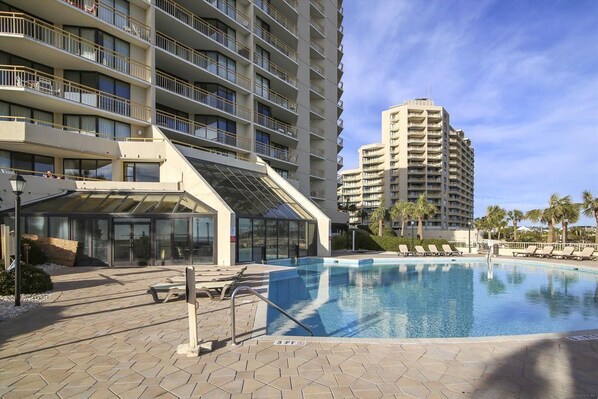 A hotel with a swimming pool, multiple balconies, and a modern architectural design.